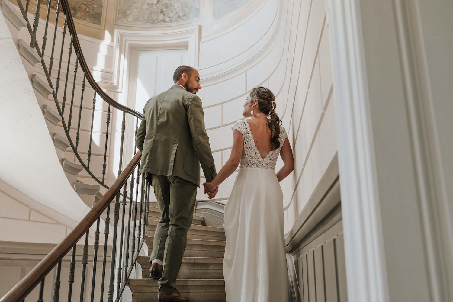 Un couple de mariés montant les escaliers de leur lieu de réception