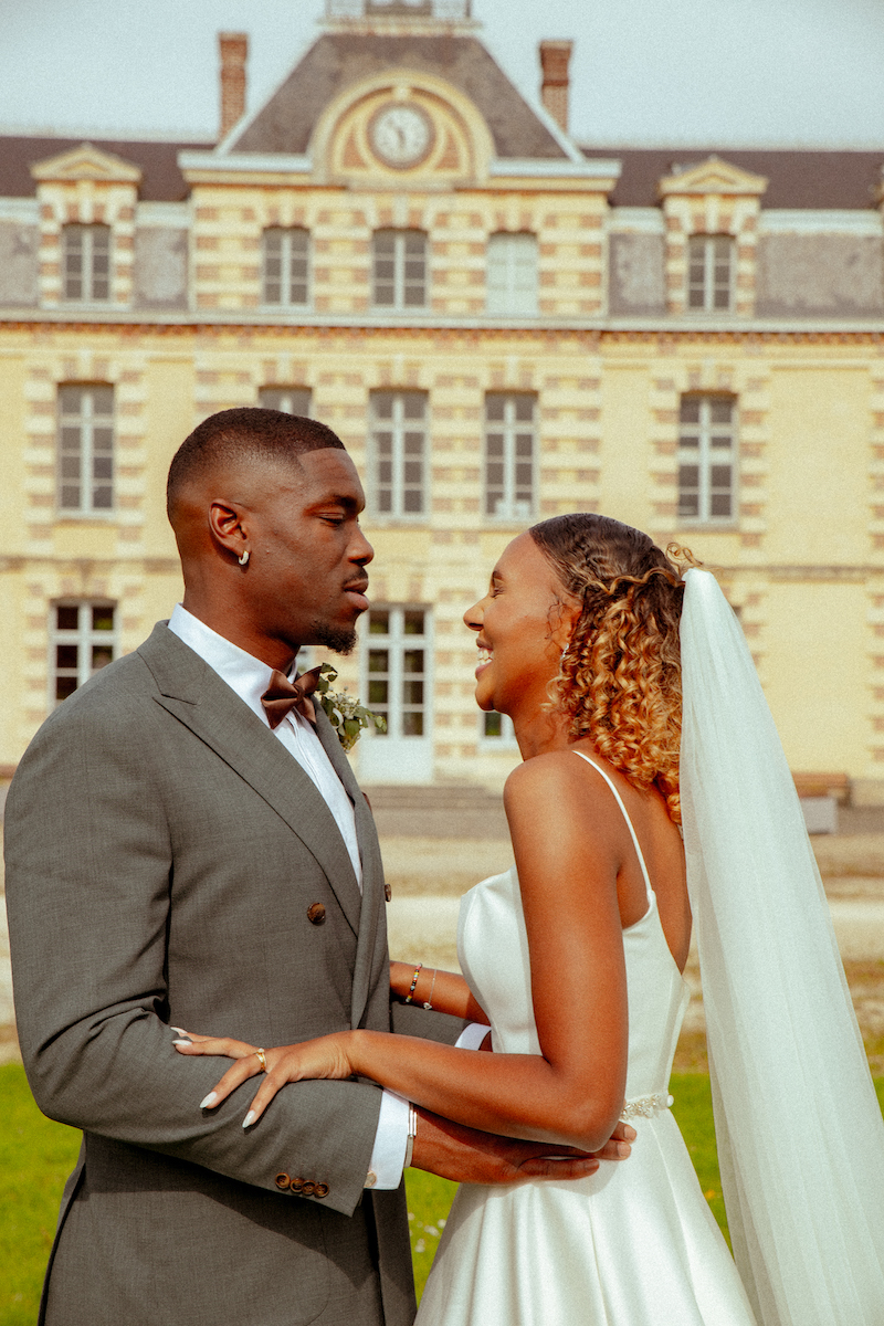 Un couple de mariés qui se regardent devant un château